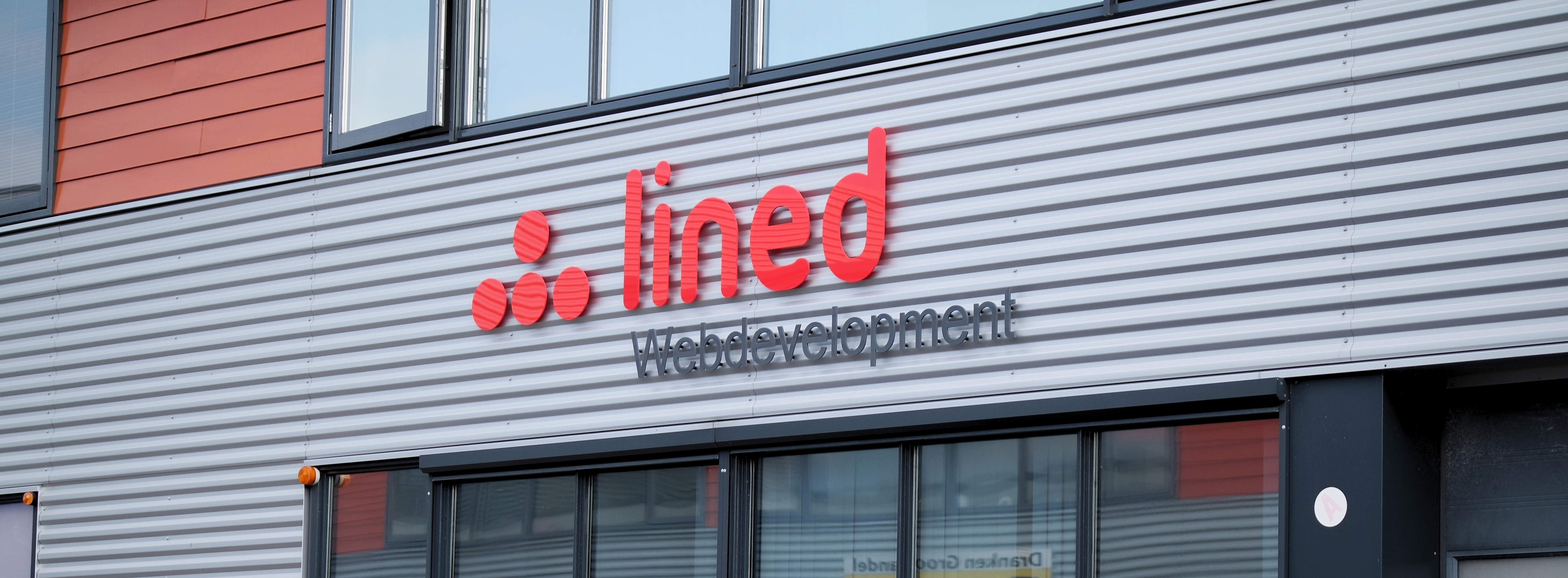 Gevel van het bedrijfspand van Lined met het rode Lined-logo